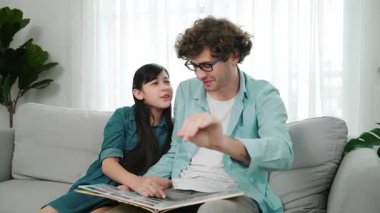 Komik liseli kız masal kitabına işaret ederken mutlu bir baba hikâyesi ve dokunaklı bir jest. Öğrenciler ebeveyn ararken peri kuyruğu hakkında konuşmaktan zevk alırlar. Aile eğlence konsepti. Pedagoji.