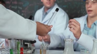 Çalışmaya hazırlanmak için kız eliyle biyokimyasal test tüpünü seçiyor. Zeki öğretmen ve bir grup mutlu çocuk BTMM fen sınıfında teoriyle kara tahtada deney yapıyorlar. Öğretim