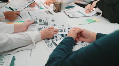 Bir iş ekibi bir ofiste işbirliği yapar, belgeleri ve çizelgeleri inceleyerek finansal verileri analiz eder. Toplantı stratejik planlama ve takım çalışmasını yansıtıyor. SACTR