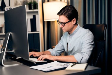 Akıllı iş adamı iş paragrafı dinamik pazarlama analizi planını analiz ediyor. Kağıt kağıtları ve bilgisayar monitörü raporlarını gece evdeki belge verileriyle karşılaştırmak için hazırlıyor. Bireysel.