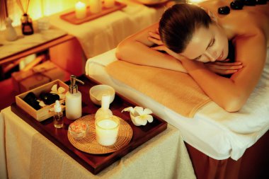 Beyaz kadın müşteri stres önleyici spa masajının keyfini çıkarıyor ve lüks otel ya da otelde sıcak mum ışığında güzellik teniyle eğleniyor. Sessiz.