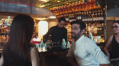 VIP grubu, barın önünde oturmuş arkadaşlarıyla ya da barmen hazırlarken karışık punç kokteyli içen çiftle yaşam tarzı seyahatlerini tartışıyor tezgahın üzerinde arka taraftaki süslü Noel ağacını hazırlıyor. Vinosity.