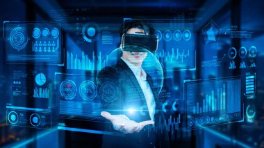 VR gözlüklü proje yöneticisi elinde mali tablo ve ofiste parlayan mavi ışık tutuyor. Yetenekli iş adamı, yapay zekadan elde edilen verileri kullanarak pazarlama stratejisini kontrol ediyor ve planlıyor.