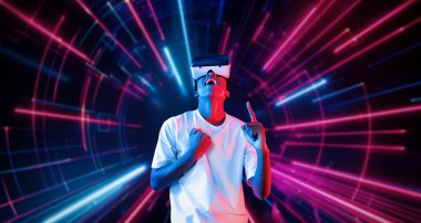 VR gözlüklü profesyonel erkek oyuncu parlayan neon ışıkla oyun oynuyor. Heyecanlı oyuncu artırılmış gerçeklik teknolojisi yeniliklerini kullanarak metaevrene bağlanmayı seviyor. Yaratıcılık.