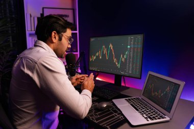 Akıllı tüccar işadamı, karanlık oda gecesinde neon ışıklı ofisteki arama pazarında yüksek kârla ekranda bilgisayar ve bilgisayar üzerinde dinamik borsa yatırımları üzerinde yoğunlaşıyor. Tahmin et..