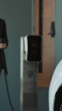 İlerici kadın evdeki elektrikli aracına şarj istasyonu fişi takıyor. EV otomobilleri çevreye yararlı temiz ve yeşil enerji kavramı sağlar.