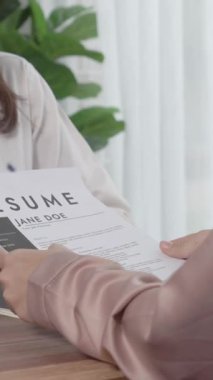 İş yerindeki profesyonel İK müdürüyle yakın çekim genç ve hevesli bir aday görüşmesi. Başvuru sahiplerini inceleyen işveren, iş görüşmesine hazırlanmak üzere işe devam ediyor.