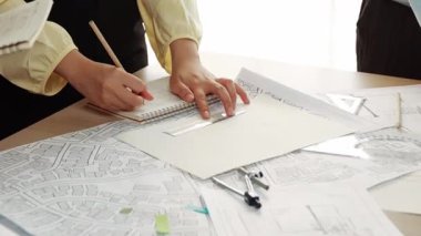 Akıllı mimar ya da akıllı mühendisin ölçüm aracı ve kalem el kullanarak mimari ofisindeki inşaat isabet planı üzerine detaylı bir yazı yazışının videosu. Eline odaklan. - Yakın çekim. Tanımlama.