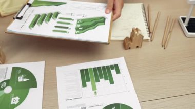 Şirketin gelecekteki EG 'si için yeşil enerji grafiği kullanımına danışmanlık ve analiz yapan iş ekibi. Yel değirmeni modeli, masadaki temiz enerji ve ev bloğu sembolize edilmiş eko evi kullanarak temsil ediliyor. Tanımlama.