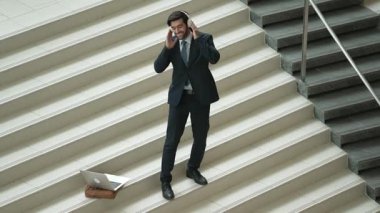Kulaklıktan müzik eşliğinde merdivenlerde duran profesyonel bir iş adamı. Merdivenlere dizüstü bilgisayar yerleştirip dans ederken dinlenme sesi dinleyen yetenekli bir proje yöneticisi. Modern dans. Sevinçli..