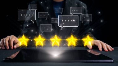 Bir işadamı, dijital geri bildirim ve müşteri memnuniyetini simgeleyen, beş yıldız ve konuşma baloncukları gösteren parlayan bir tabletle etkileşime girer. Dörtgen
