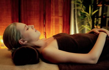 Beyaz kadın müşteri stres önleyici spa masajının keyfini çıkarıyor ve lüks otel ya da otelde sıcak mum ışığında güzellik teniyle eğleniyor. Sessiz.
