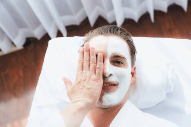 Kaplıca salonunun sakin atmosferi, insan müşterisi modern gün ışığında lüks yüz kremi masajıyla kendini yenileme zevkine kapılıyor. Yüz bakımı ve güzellik konsepti. Sessiz.