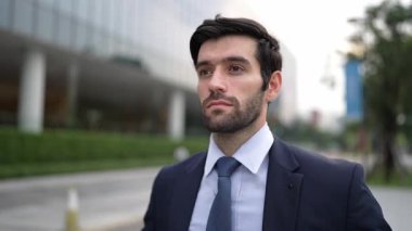Şehir manzarasında kameranın yanında yürüyen iş adamının yakın çekimi. Proje yöneticisi bulanık arkaplanlı olarak iş yerine gidiyor. Yakışıklı yatırımcı resmi takım elbise giyer, görüşmeye hazırlanır, iş görüşmesi yapar. Sevinçli..