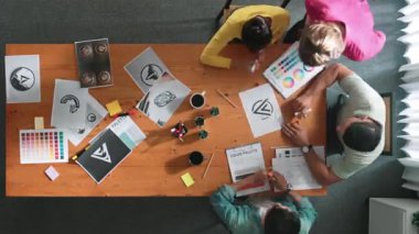 Proje yöneticisi renk paletleri seçerken tasarımcının tablete baktığı yukarıdan aşağıya hava görüntüsü. Yetenekli grafik tasarımının zaman aşımı ve logoya bak. Yetenekli ekip grafikleri seçiyor. Sempozyum.