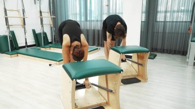 Müşteriler pilates antrenmanı sırasında ayakta gerinme egzersizi yapıyorlar. Esnekliği artırmak için. Spor salonunda bacak dayanıklılığı. Çekici grup esniyor ve eğiliyor. Alışkanlık.