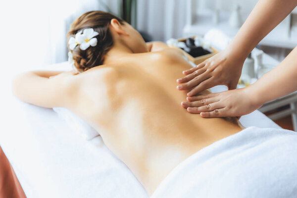 Caucasian woman customer enjoying relaxing anti-stress spa massage and pampering with beauty skin recreation leisure in day light ambient salon spa at luxury resort or hotel. Quiescent