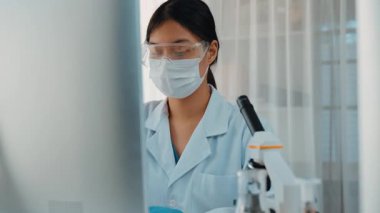 Laboratuvar kimya araştırmacısı mikroskop ve dizüstü bilgisayar kullanarak yeni ilaç ya da tedavi geliştirir. Bilimsel uzmanlığa ve laboratuvar mikrobiyoloji ekipmanlarına sahip sağlık teknolojisi. Ağır çekim. Katı.