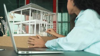 Laptop analizi ev modeli yapısını kullanan İspanyol mimar el mühendislerinin yakın çekimi. Proje yöneticisi dizüstü bilgisayarda yazarken ev modeli inşaatını kontrol ediyor. Tasarım konsepti. Yönlendirici.