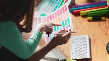 Akıllı tasarımcının renkli paletlerden renk seçmesine yardım ederken yukarıdan aşağı görünümü. Dizüstü bilgisayardan logoya bakarken birlikte çalışan ve planlayan iş adamlarının hava görüntüsü. Sempozyum.