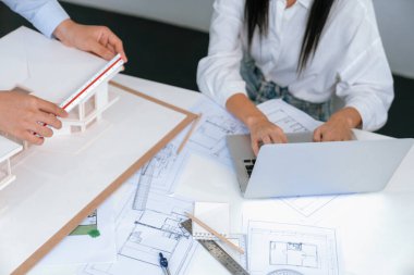 Profesyonel mühendis ev modelini tartartarken, yetenekli tasarımcı da planına yazar. Birlikte çalışmak, işbirliği, işbirliği. Yaratıcı tasarım ve takım çalışması konsepti. Üst Manzara. Tertemiz..