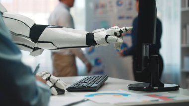 Çağdaş bir ofiste verileri gösteren, üretken bir iş ortamında takım çalışması ve teknolojiyi ön plana çıkaran bir robot kol. Noogenesis