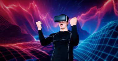 Yetenekli oyuncular video oyununda zaferi kutlarken mavi ve pembe soyut arka planda VR kulaklık takıyorlar. Siyahi vücutlu profesyonel bir adam ayakta durup kazanmayı kutluyor. Yaratıcılık.