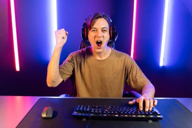 Kazanmak için çevrimiçi oyun oynayan akıllı flama makinesinin sunucu kanalı, neon ışıklı odada seçilen takım yarışması için izleyicilerle birlikte canlı yayında canlı yayında kulaklık takıyor. Bireysel.