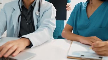 Hastane masasında birlikte çalışan ve tıbbi tedavi planlayan çeşitli profesyonel sağlık görevlileri. Takım çalışması başarılı hastalıklara ve hastalıklara yol açar. Ağır çekim. Katı.