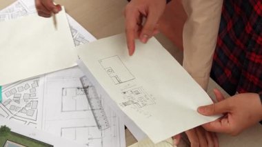 Mimari döküman, ölçüm araçları ve ahşap blokların modern ofiste etrafa saçıldığı masa üzerine planlar yapma konusunda akıllı mimar ve güvenlik mühendisi tartışması. - Yakın çekim. Tanımlama.