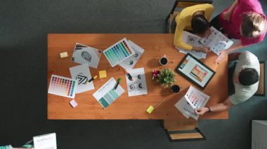 Proje yöneticisi renk paletleri seçerken tasarımcının tablete baktığı yukarıdan aşağıya hava görüntüsü. Yetenekli grafik tasarımının zaman aşımı ve logoya bak. Yetenekli ekip grafikleri seçiyor. Sempozyum.
