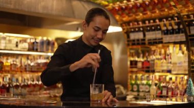 Zeki Asyalı barmen, bardakta karıştırılmış alkol şurubunu buzla karıştırıyor. Lüks gece kulübünde gece hayatı karışımı sergilenen özel bir içecek. Vinosity.