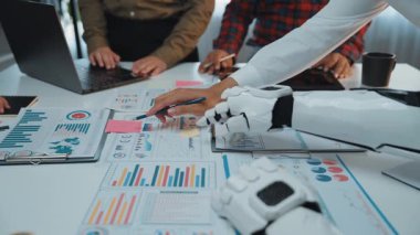 Profesyonellerin iş analizi ve stratejisini geliştirmek için bir yapay zeka asistanıyla birlikte çalıştığı bir şirket ortamı, teknolojinin modern işyerlerindeki rolünü vurguluyor. Noogenesis Yapay Zeka