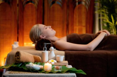 Aromaterapi masajı ambiyansı ya da spa salonu kompozisyon düzeneği bulanık kadınlara odaklı dekor mumları ve spa aksesuarları ile tatil köyü veya otel arka planında keyifli aroma spa masajı yapan. Sessiz.
