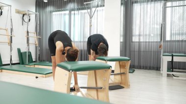 Müşteriler pilates antrenmanı sırasında ayakta gerinme egzersizi yapıyorlar. Esnekliği artırmak için. Spor salonunda bacak dayanıklılığı. Çekici grup esniyor ve eğiliyor. Alışkanlık.