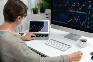 Bilgisayar ve dizüstü bilgisayarı kullanarak, çalışma masasındaki dinamik artırılmış borsa grafiğinin en yüksek kar değerini araştıran bir tüccar, modern ofisteki ekrandaki döviz kuru değerini analiz ediyor. Bireysel.