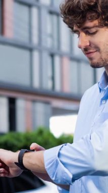 İş adamı, şarj istasyonundan şarj olurken akıllı hareketten hologramda EV akü durumunu kontrol ediyor. Modern şehir yaşam tarzı ve karbondioksiti azaltmak için çevre dostu elektrikli araba kullanımı. İnceleyin