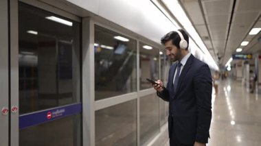 Proje yöneticisi, tren istasyonunda cep telefonu ve arama ekibi tutarken kulaklık takıyor. Zeki iş adamı bulanık bir geçmişi olan treni beklerken rahatlatıcı müzik dinliyor. Sevinçli..