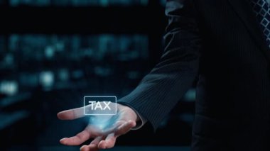 Parlak vergi simgeleriyle etkileşime giren bir işadamı, teknolojinin vergi yönetimi ve finansal planlama alanlarına entegrasyonunu bir şirket ortamında sergiliyor. Dörtgen