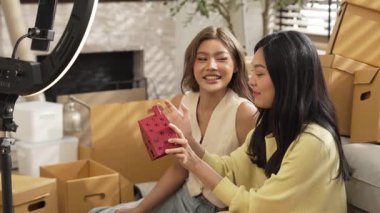 Satıcı çevrimiçi platformu kullanarak canlı yayın yaparken ürünü incelemek ve satmak için birlikte çalışıyor. Zeki Asyalı girişimci soruları cevaplarken ürün gösteriyor. Medya. Yan görüş. Myrmidon.