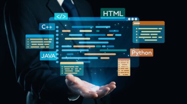 Bir işadamı programlama dilleri ve kod parçalarıyla dolu sanal bir arayüz sunar. Bu görüntü yazılım geliştirme ve kodlama eğitiminde teknolojik yeniliği temsil etmektedir. Dörtgen