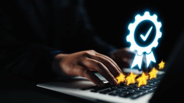 Bir dizüstü bilgisayarda yazı yazan ellerin yakın çekimi, parlak bir sertifika rozeti ve yıldızlarla tamamlanmış, dijital bir çalışma alanında elde edilen başarıyı ve olumlu geri bildirimi temsil ediyor. Dörtgen