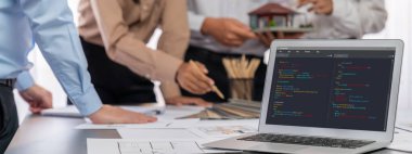 İç mimar tasarımcı grubu, daha kesin tasarım için planlar ve dizüstü bilgisayar ekran mimari yazılımı üzerinde birlikte tartışıyorlar. Modern ev tasarımı ve yenileme. İçgörü