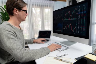 Bilgisayar ve dizüstü bilgisayarı kullanarak, çalışma masasındaki dinamik artırılmış borsa grafiğinin en yüksek kar değerini araştıran bir tüccar, modern ofisteki ekrandaki döviz kuru değerini analiz ediyor. Bireysel.