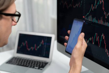 Akıllı borsa yatırımcıları ekranda akıllı telefon ile piyasa borsasını işaret ederek dizüstü bilgisayarın yanı sıra en yüksek dinamik yatırım oranını göstererek, modern işyerindeki veri planlamasına odaklanıyorlar. Bireysel.