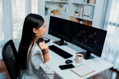 Başarılı genç Asyalı iş kadını, modern ofisteki bilgisayar ekranlarında dinamik iş grafiği üzerine borsada yumruklaşarak en yüksek karı elde ediyor, finansal teknolojiyi analiz ediyor. Taktik.