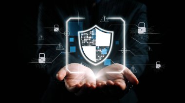 Dijital bir kalkanı tutan ellerin çarpıcı görüntüsü, modern bir dijital ortamda veri ve bilginin korunmasında siber güvenliğin önemini sembolize eder. Dörtgen