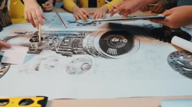 Bir grup mühendis, teknik çizimler, aletler ve makine parçalarıyla dolu bir masada birlikte çalışıyorlar. Fikirleri tartışıyor, tasarımları analiz ediyor ve gelecek projeleri planlıyorlar. SACTR