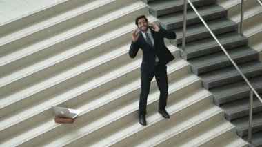 Kulaklıktan müzik eşliğinde merdivenlerde duran profesyonel bir iş adamı. Merdivenlere dizüstü bilgisayar yerleştirip dans ederken dinlenme sesi dinleyen yetenekli bir proje yöneticisi. Modern dans. Sevinçli..