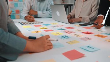 İşbirlikçi bir beyin fırtınası sırasında dinamik bir çalışma alanı, dizüstü bilgisayarlar ve renkli yapışkan notlarla uğraşan takım üyelerini sergilemek, yaratıcılığı ve yeniliği teşvik etmek. SACTR